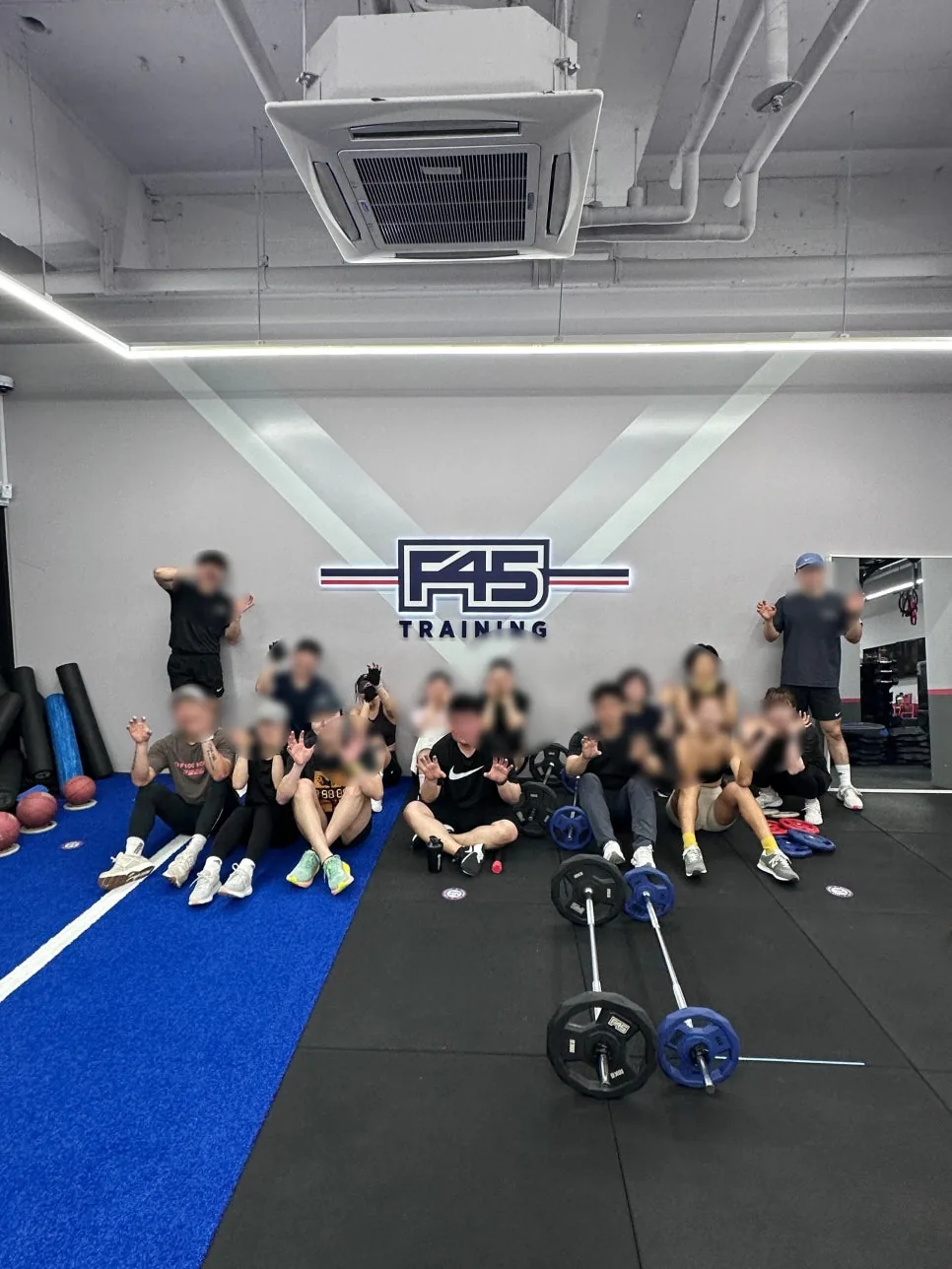 수업을 마치고 F45 로고 벽 앞에 모여 앉은 회원들
