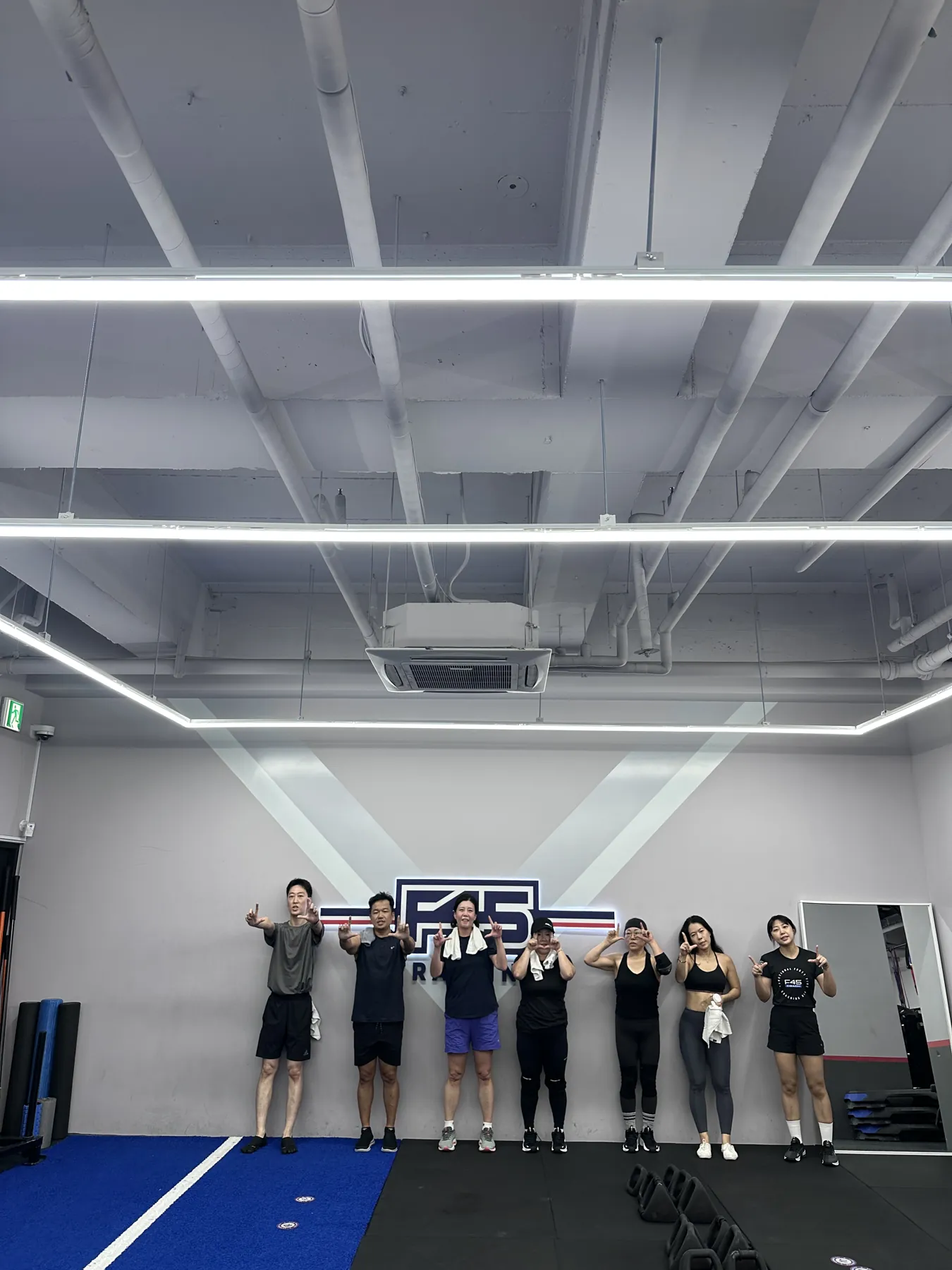 F45 로고 벽 앞에서 포즈를 취한 F45 미사 팀